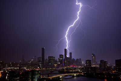 Lightning over illuminated buildings in city at night