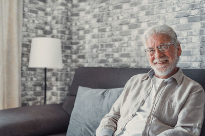 Portrait of senior man sitting on sofa at home