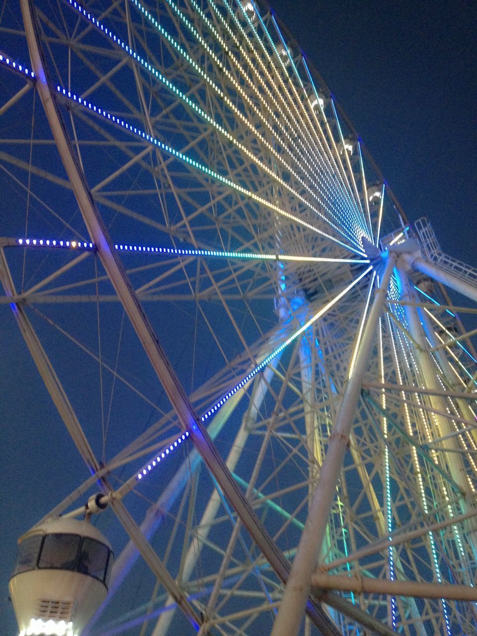 ferris wheel, amusement park ride, amusement park, arts culture and entertainment, low angle view, illuminated, built structure, night, architecture, sky, clear sky, outdoors, no people, fun, metal, big wheel, city, travel destinations, blue, building exterior