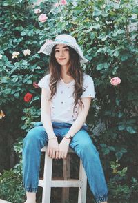 Portrait of beautiful young woman sitting against plants