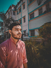 Young man standing against buildings in city