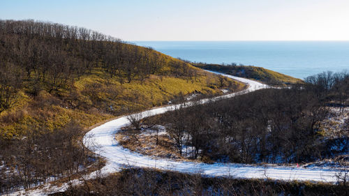 Scenic view of road by sea against sky