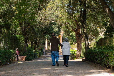 Rear view of couple walking along plants