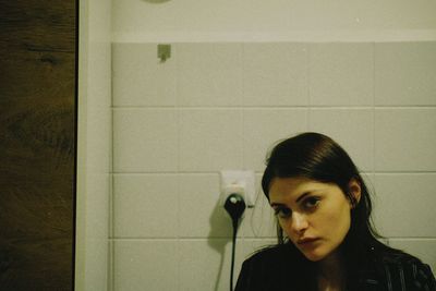 Young woman standing against wall