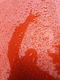 Full frame shot of wet metal with shadow of person waving 