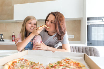 Daughter feeding pizza to mother at home