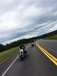 People riding motorcycle on road against sky