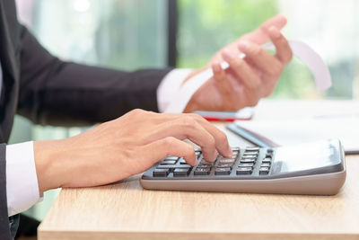 Midsection of man using mobile phone on table