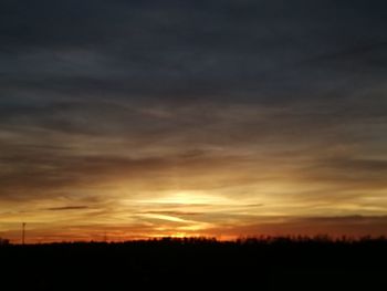 Silhouette landscape against dramatic sky during sunset