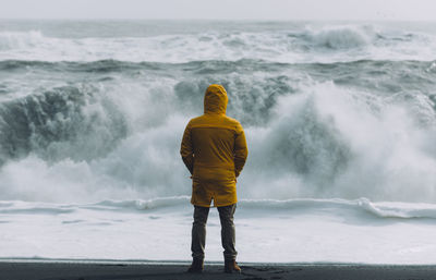 Rear view of man standing against sea