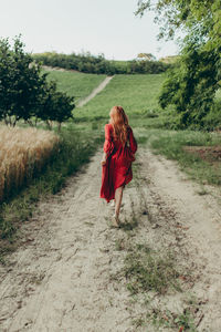 Rear view of woman running on a pathway in the countryside
