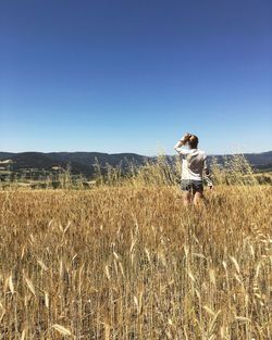 Woman standing on field against clear sky