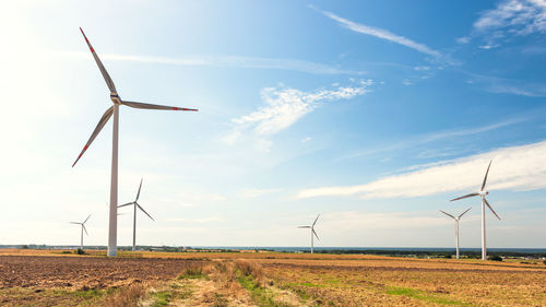 Windmills on field against sky