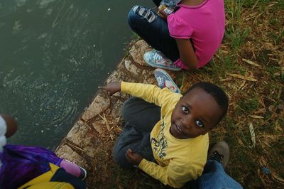 High angle portrait of cute boy pointing towards lake