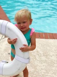 High angle view of girl holding life belt while standing at poolside