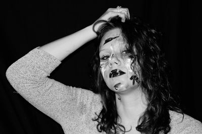 Portrait of young woman against black background