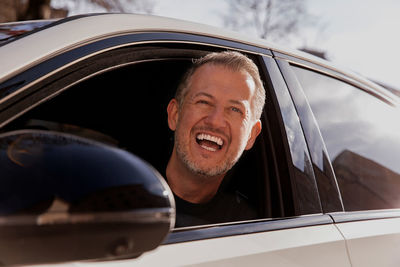 Happy smiling attractive businessman in a casual cloth driving a car in the city, test drive