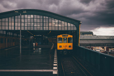 Train at railroad station against cloudy sky