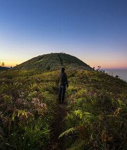 Rear view of man standing on mountain against sky