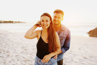 Portrait of smiling young woman standing on beach