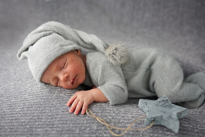 Cute newborn baby sleeping on gray blanket and holding craft wooden star. bed vibes.