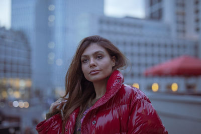 Close-up of thoughtful young woman wearing warm clothing in city during sunset