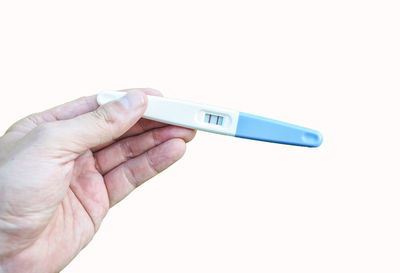 Close-up of hand holding eyeglasses against white background