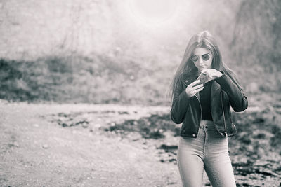 Young woman using mobile phone while standing outdoors