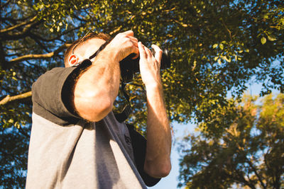 Low angle view of man holding autumn tree