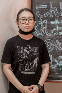 Portrait of young woman standing against wall