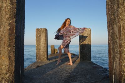 Woman standing by sea against clear sky