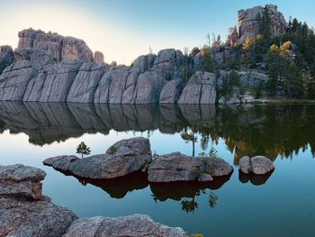 Reflection of rock formation in lake against clear sky