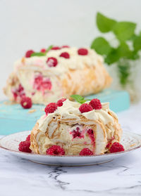 Baked meringue roll with cream and fresh red raspberry, white background