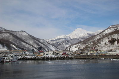 Scenic view of lake by snowcapped mountains against sky