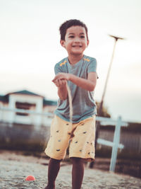 Portrait of cute boy standing against sky