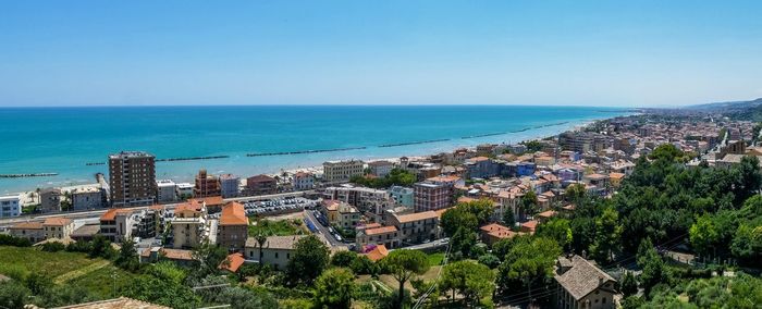 High angle view of townscape by sea against clear sky