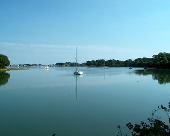 Boats in calm lake against blue sky