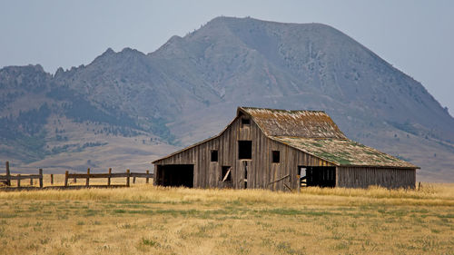 Abandoned house on field by mountains against sky