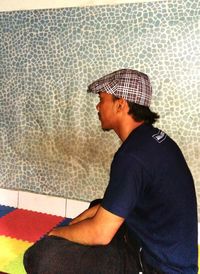 Side view of young man looking away against wall