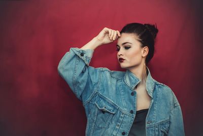 Portrait of woman standing against red background