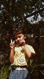 Cute girl holding plant against trees