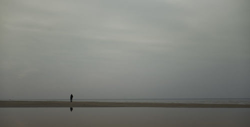 Silhouette of person on beach against sky