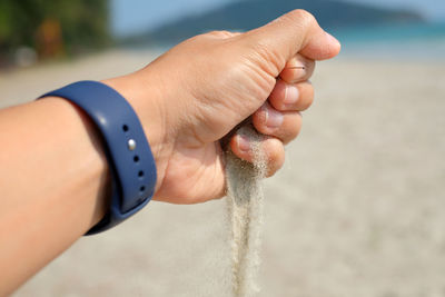 Close-up of man hand on sea shore