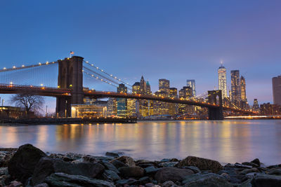 Illuminated bridge over river with city in background