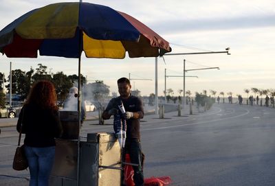 Men standing on road in city against sky