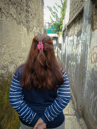 Rear view of woman standing against wall