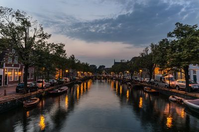 Canal amidst illuminated trees against sky