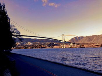 Bridge over frozen lake against sky during sunset