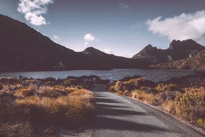 Scenic view of road by mountains against sky