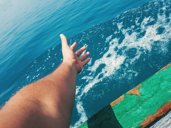 Cropped hand of man gesturing while traveling on boat in sea